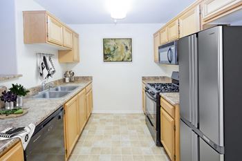 a kitchen with wooden cabinets and stainless steel appliances at Dronfield Astoria Apartments , California